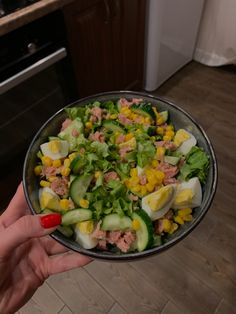 a person holding a bowl filled with salad