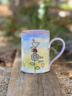 a ceramic mug with the words be you on it sitting on a piece of wood