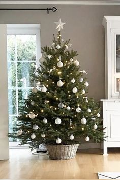 a white christmas tree in a room with wooden flooring and lights on the top