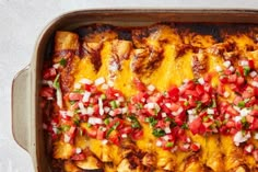 an enchilada dish with tomatoes, onions and green peppers in a casserole pan