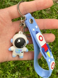 a hand holding a blue plastic toy with a spaceman keychain attached to it