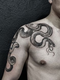 a man's chest with a snake tattoo on his left arm and chest is shown