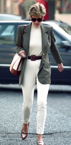 a woman walking down the street in white pants and a blazer jacket with brown heels