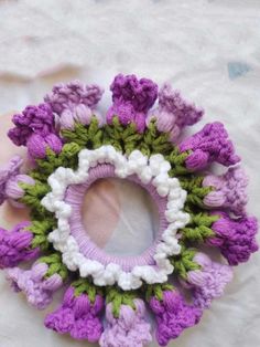 a crocheted purple and white ring with green leaves