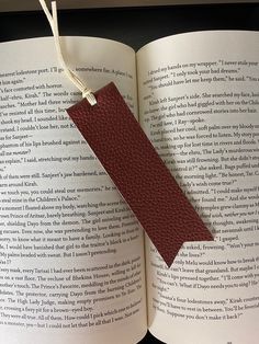 an open book with a red leather tag attached to it's front cover and bottom pages