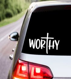 a car with the word worthy written on it's back window is parked in front of a road