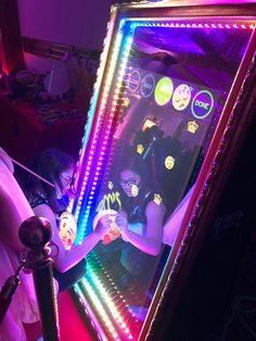 a woman standing in front of a mirror with lights on it