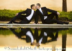 two men in suits sitting on the ground kissing