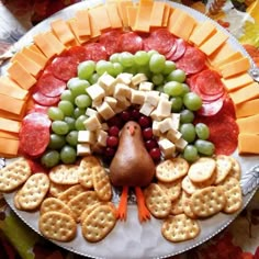 a turkey shaped platter with crackers, grapes, and cheeses on it