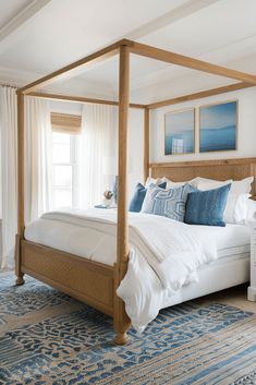 a bed with white sheets and blue pillows in a bedroom next to a large window