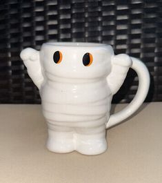 a white cup with an orange eyes on it