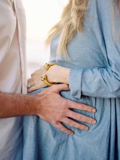 a man and woman standing next to each other with their hands on their stomachs