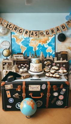 a cake and cupcakes sitting on top of a suitcase in front of a world map