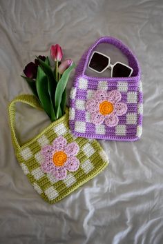 two crocheted purses sitting on top of a bed next to each other