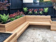 a wooden bench sitting in the middle of a garden filled with plants and potted plants