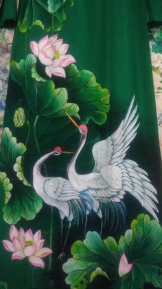 a green shirt with two white birds and flowers on it