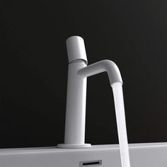 a white faucet sitting on top of a sink next to a black wall