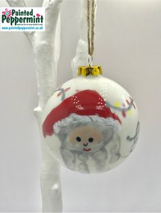 a glass ornament hanging from a tree with a santa clause hat on it