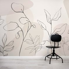 a chair sitting in front of a wall with flowers painted on it