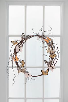 a wreath made out of branches and flowers sitting on a window sill in front of a white wall