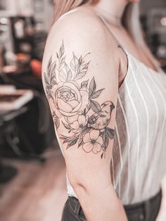 a woman with a flower tattoo on her arm and shoulder, looking at the camera