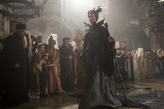 a group of people standing around each other in front of a man dressed as maleficent