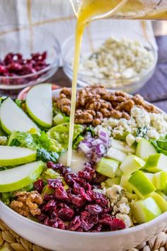 apples, cranberries, walnuts and other ingredients are being poured into a bowl