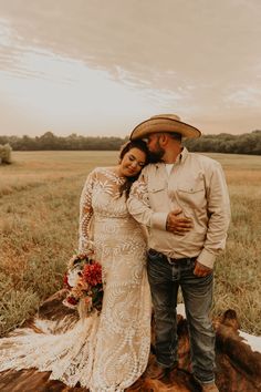 a bride and groom standing on a log in the middle of a field