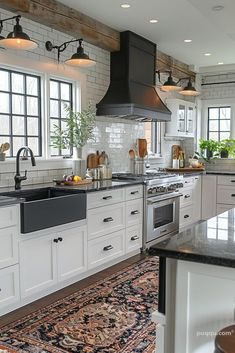 a kitchen with white cabinets and black counter tops, an area rug on the floor