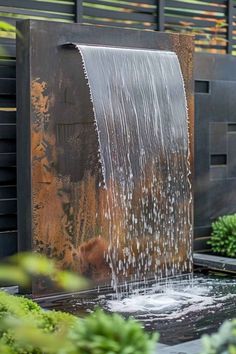 an outdoor fountain with water flowing from it's sides and green plants in the background