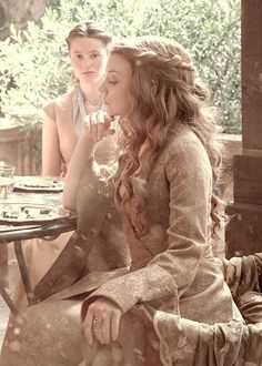 two women sitting at an outdoor table talking