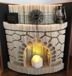 an open book sculpture with a lit candle in it's center and some books stacked on top