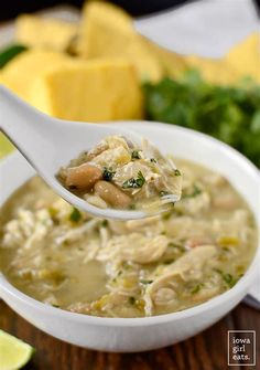 a spoonful of chicken and spinach soup with tofu cubes in the background