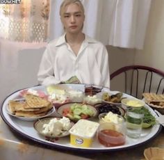 a person sitting at a table with plates of food in front of them on the television screen