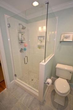 a white toilet sitting next to a shower in a bathroom on top of a tiled floor