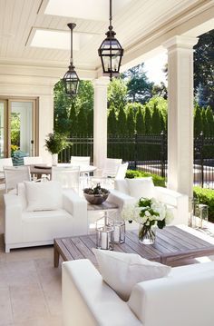 a living room filled with white furniture next to a patio covered in plants and trees