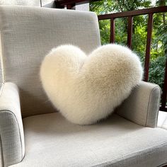 a white heart shaped pillow sitting on top of a chair