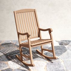 a wooden rocking chair sitting on top of a stone floor