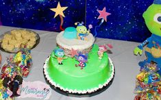 there is a green cake with stars on it and other decorations around the cake table