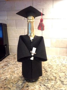 a bottle with a graduation cap and gown on it sitting on top of a counter