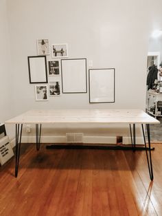 a white table sitting on top of a hard wood floor next to pictures and frames