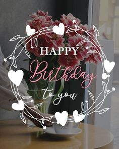 a happy birthday card with pink flowers in a vase on a table next to a window