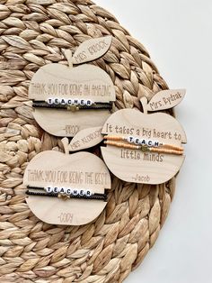 three wooden apple shaped magnets with writing on them sitting on a woven place mat