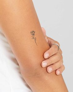 a woman's arm with a small rose tattoo on the left side of her arm