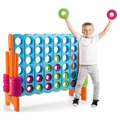 a young boy is holding two large toy discs in front of an interactive game board