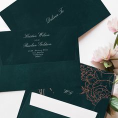 the wedding stationery is set on top of two envelopes with flowers in them