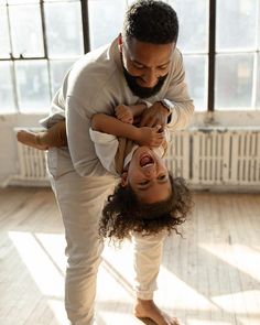 a man holding a woman in his arms while they both laugh and stand on the floor