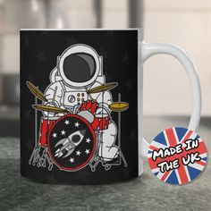 a coffee mug with an astronaut playing the drums on it, and a sticker that says made in the uk