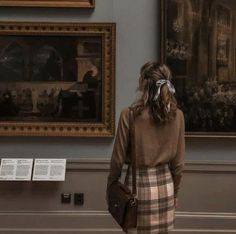 a woman is standing in front of paintings and talking on her cell phone at the museum