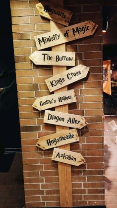 a wooden sign that is on the side of a brick wall with arrows pointing to different locations